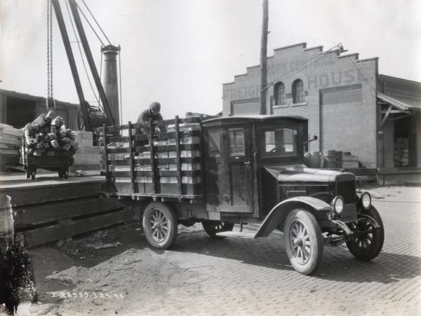 A man loading boxes onto the bed of a Model S International truck.