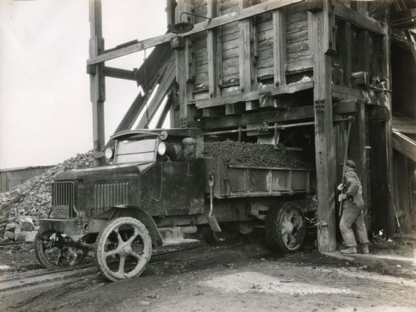 Men fill the bed of a Model 103 International truck with cinders from a chute at the Solway Process Company plant.
