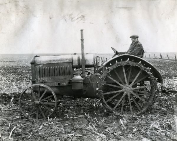 M.D. Stocking posing for a photograph while sitting on his McCormick-Deering 15-30 tractor in a harvested farm field.
