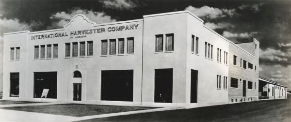 Exterior view of the San Antonio branch building of the International Harvester Company. The front of the building appears to be a modern addition to the brick section behind it. A loading dock appears in the background.