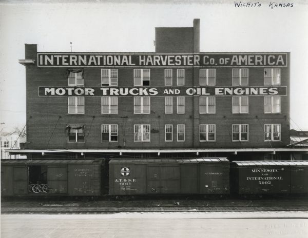 Several railroad cars resting on the tracks in front of International Harvester Company's Wichita branch building.