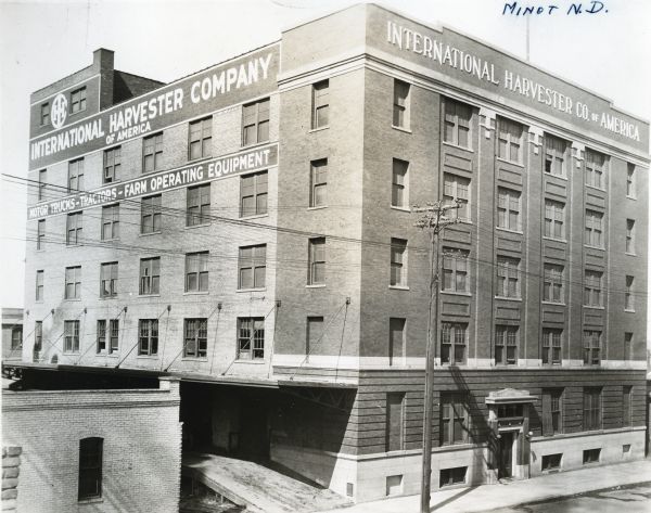 Exterior view of International Harvester Company's Minot branch building. The signs on the building read, "International Harvester Company of America" and "Motor Trucks - Tractors - Farm Operating Equipment."