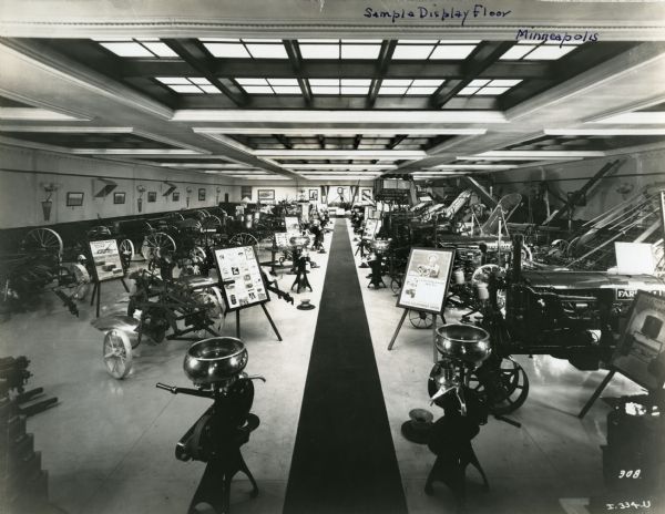 Cream separators, tractors, other farm equipment, and informational signs are arranged on a display floor inside International Harvester Company's Minneapolis branch house.