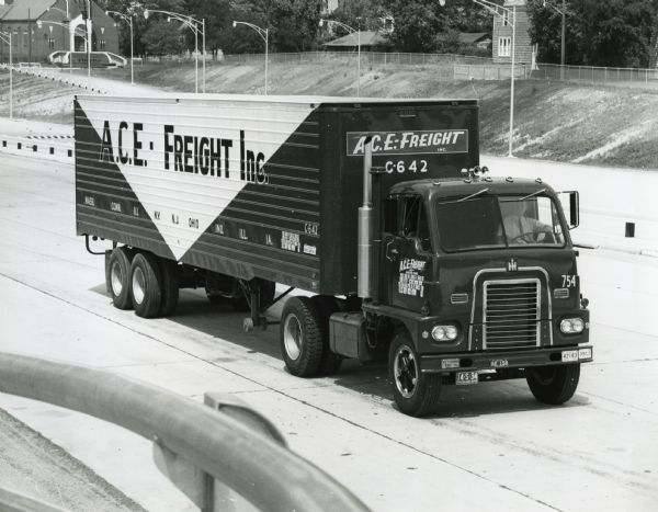 Three-quarter front view of an International model DCO-405 truck owned by A.C.E. Freight Incorporated as it drives along a highway.