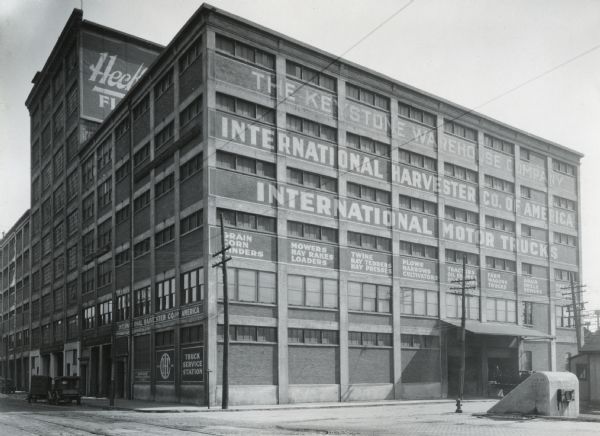 Exterior view of International Harvester Company's Buffalo branch building. The words on the building's exterior read, "The Keystone Warehouse Company. International Harvester Co. of America. International Motor Trucks. Grain, corn, grinders, mowers, hay rakes, Loaders, Twine, Hay Tedders, Hay Presses, Plows, Harrows, Cultivators, Tractors, Oil Engines, Farm Wagons, Trucks, Grain Drills, Sowers..."