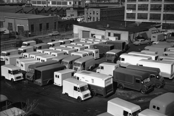 Elevated view of International Metro trucks in a parking lot beside factory buildings.