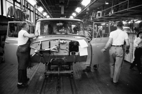 Factory workers work on partially-assembled trucks as they move down an assembly line at International Harvester's Springfield Works.