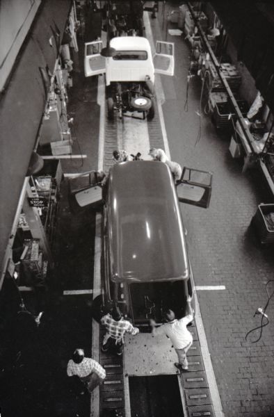 Overhead view of men working on trucks as they move down an assembly line at an International Harvester factory, possibly in Springfield, Ohio.
