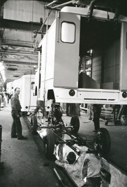 Men work on a partially-assembled Metro truck body raised on an assembly line inside the factory of the Metropolitan Body Company, an International Harvester subsidiary.