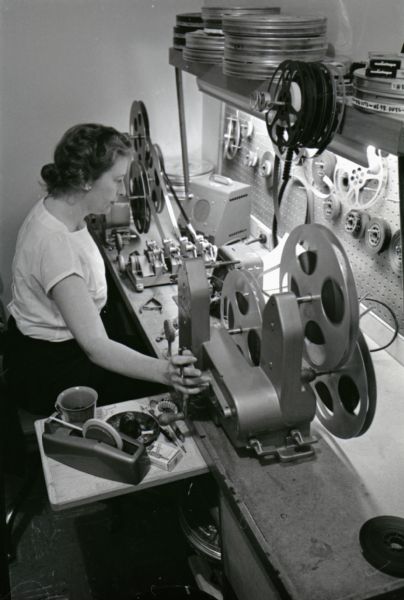 A woman spools motion picture film onto a reel at International Harvester's Hickory Hill Farm.