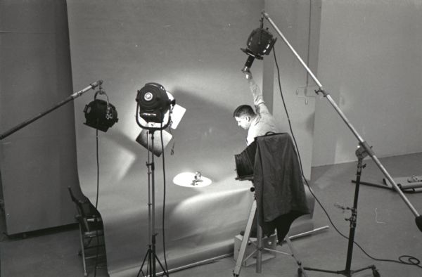 A man adjusts a light at International Harvester's Hickory Hill studio while preparing to photograph a ball bearing for the company's catalog.