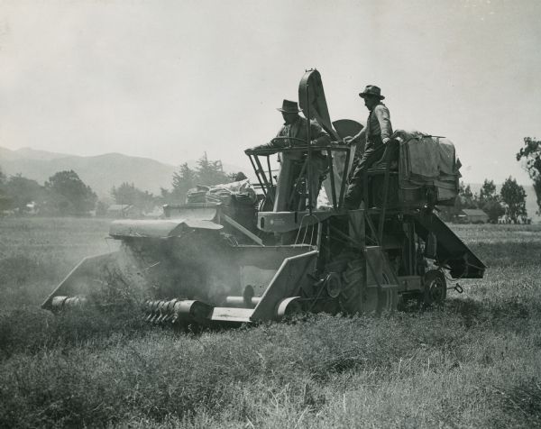 Two men harvesting with a McCormick-Deering 123-SP harvester-thresher (combine) in a field.
