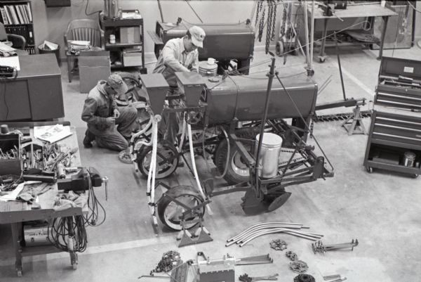 Elevated view of mechanics working with a farm machinery at International Harvester's Hickory Hill Farm.