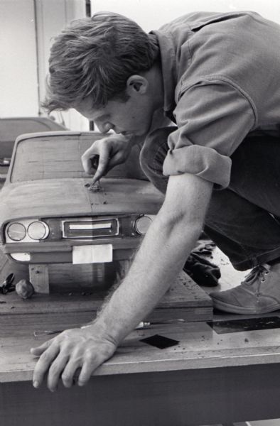 A man, possibly sculptor Howard Hastings, leans over a clay model of a "Multipurpose Safety Utility Vehicle" during the first styling seminar at the Fort Wayne motor truck engineering department. The program lasted ten weeks and participants were college students in their junior year.