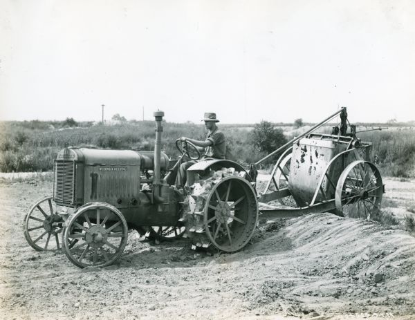 A man wearing a hat drives a McCormick-Deering 10-20(?) tractor while pulling an unidentified implement. A handwritten note underneath the image reads: "New Orleans."