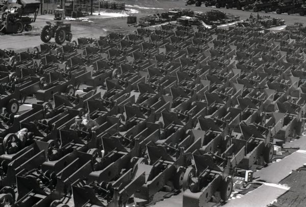 Elevated view of balers arranged in rows inside International Harvester's Memphis Works factory. Three men are standing among the balers.