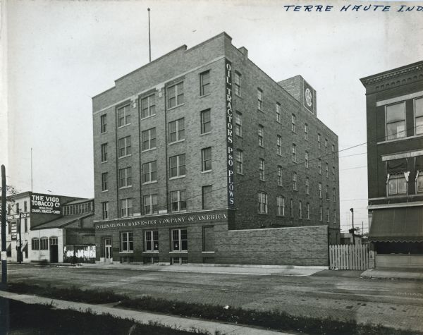Exterior view from across street of International Harvester's Terre Haute branch building, standing along a commercial strip. The Vigo Tobacco Company stands at left.