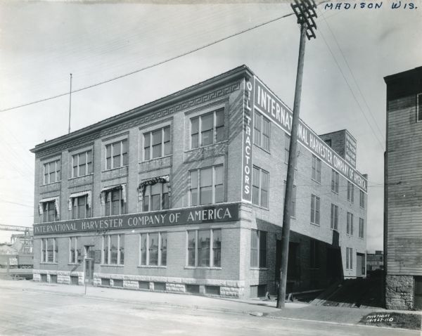 Exterior view of an International Harvester branch office building in Madison. Signs painted on the brick read "Oil Tractors," "Farm Machines, Oil Tractors, P&O Plows, Motor Trucks."