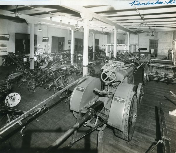 A McCormick-Deering 10-20 tractor and several pieces of and agricultural equipment stand on display inside International Harvester's Kankakee branch office showroom.