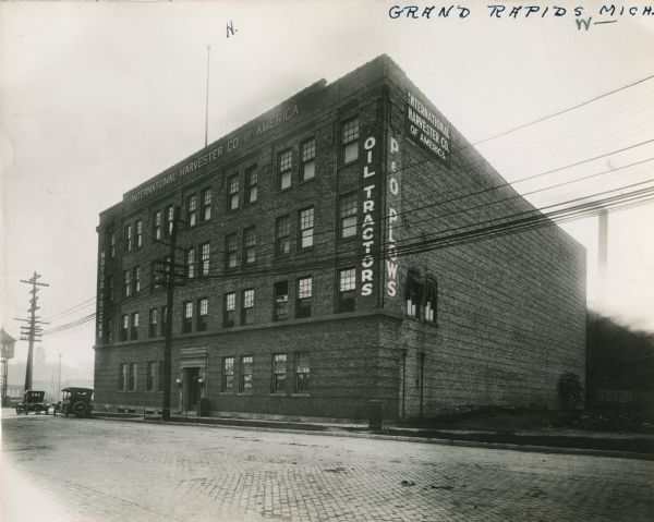 Exterior view of an International Harvester branch house at Grand Rapids. The signs painted on the building advertise "Oil Tractors" and "P&O Plows."
