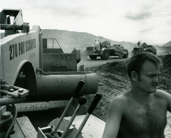 A man is using an International Harvester tractor to level land before building barracks in Vietnam.