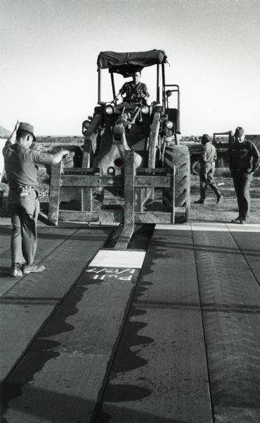 Men from the Air Force's Red Horse heavy repair squadrons use an International Harvester pay scraper to make repairs on a runway in Vietnam.