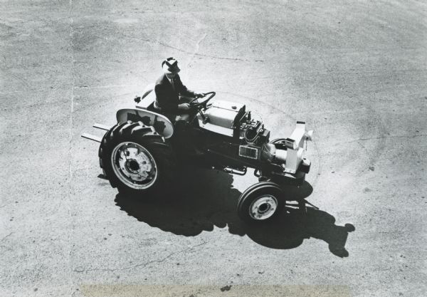 Elevated view of a man driving an International Harvester HT-340 research tractor.