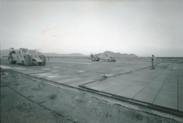 A man directs International pay scrapers along a runway at Phan Rang air force base in Vietnam.