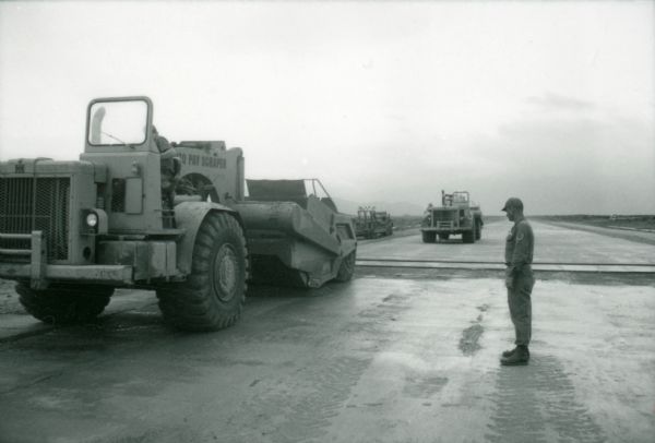 A man stands beside an International 270 pay scraper at Phan Rang, an air base in South Vietnam.