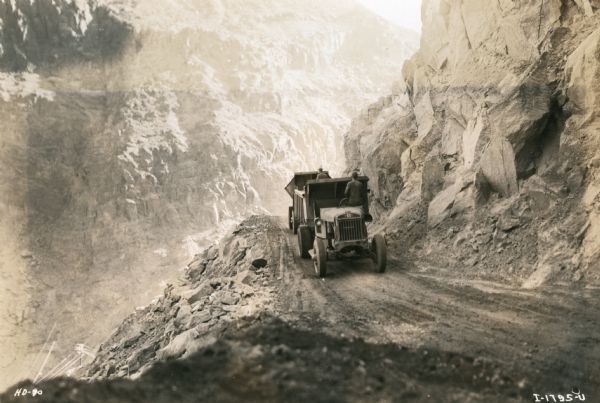 Workers use an International truck to haul building material up and down the dirt roads of a canyon during the construction of the Hoover Dam.
