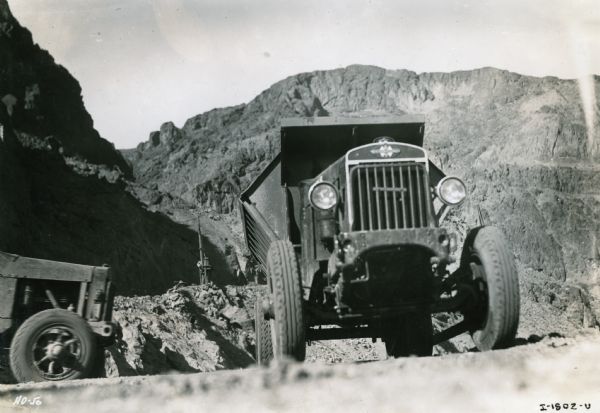 View of front of International truck ascending a dirt road during the construction of the Hoover Dam.