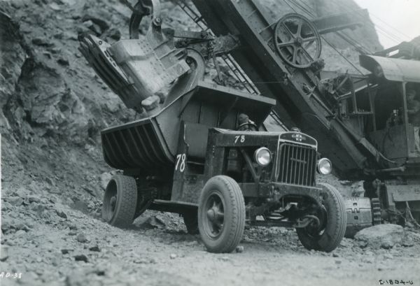 A shovel unloads boulder pieces into the back of an International truck during the construction of the Hoover Dam.
