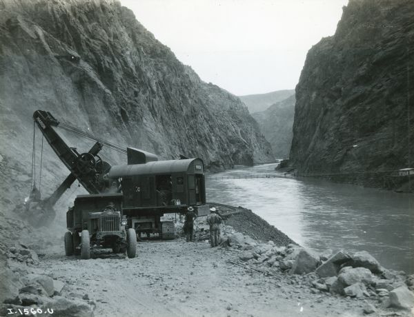An International truck waits to be loaded with boulders blasted from the walls of Black Canyon during the construction of the Hoover Dam. The Colorado River runs through the canyon at right.