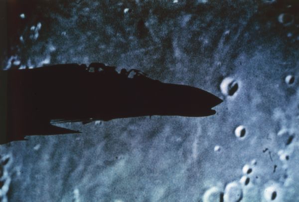 Photograph of the Phantom II jet silhouetted against what appears to be the surface of the moon.