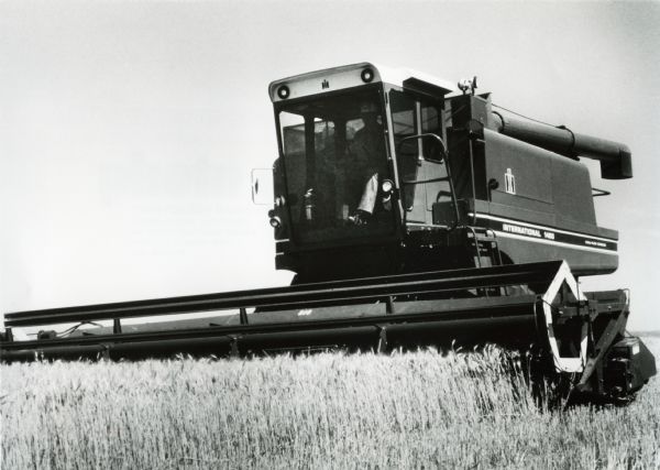 A man uses an International Harvester axial-flow combine to work in a field.