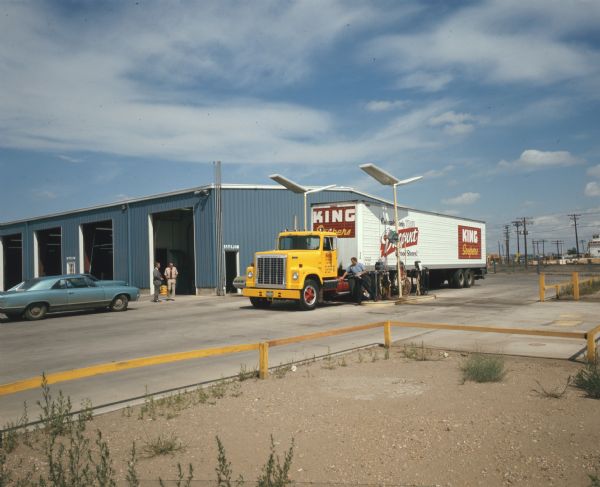 Color photograph of a man filling an International Transtar 4200 truck with gasoline at a truck stop. The signs on the trailer of the truck read: "King Soopers, Colorado's Only True Discount Food Stores."