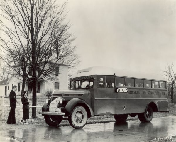 Students boarding an International D-30 bus for school. A house is in the background. The bus was equipped with  a 179-inch wheel base and a Union City body.