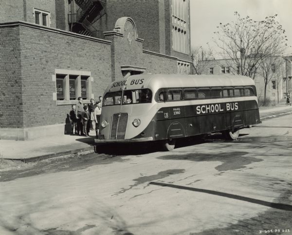 Children standing in line, boarding an International D-300 bus near what appears to be a school building. This bus was equipped with 165" Hicks body.