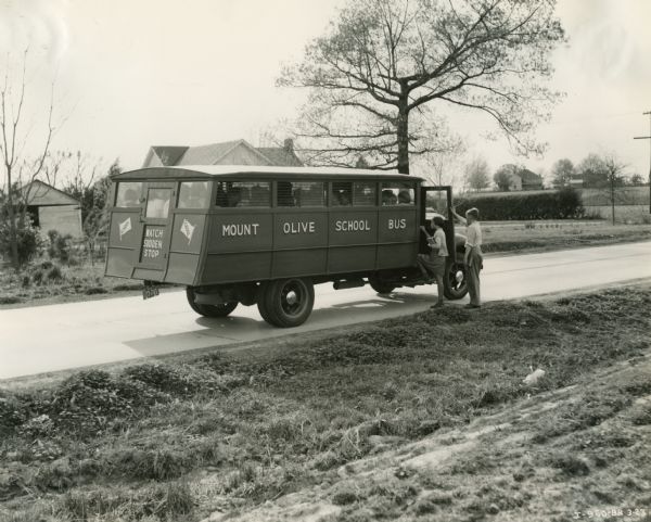 International D-30 bus picking up two students on a rural road in the Mount Olive school district. This bus was equipped with a 155-inch wheel base and a 16 foot Picayune body.