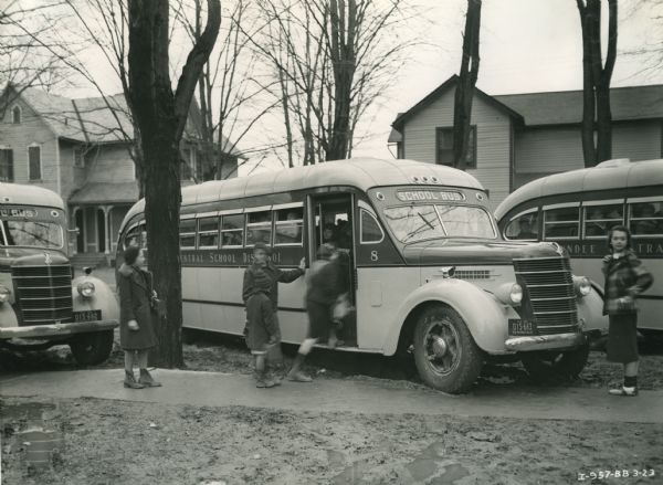 Three International buses parked across a sidewalk. Children are standing on the sidewalk. The buses were equipped with Penn-Fan bodies.