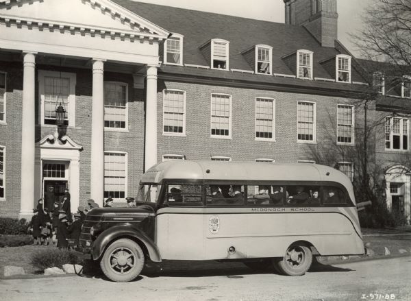 Students wearing uniform jackets and hats disembarking an International D-30 bus at McDonogh School. This bus was equipped with a Bender body style.