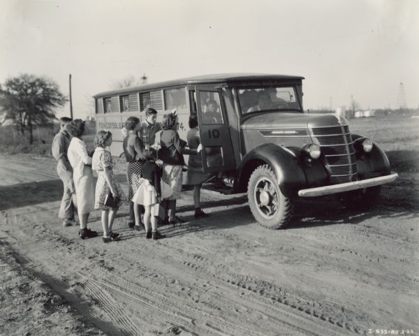 Students standing in line, boarding an International D-35 bus with a Picayune body and 179-inch wheel base. The bus belonged to the Fox Consolidated School District, No. 74.