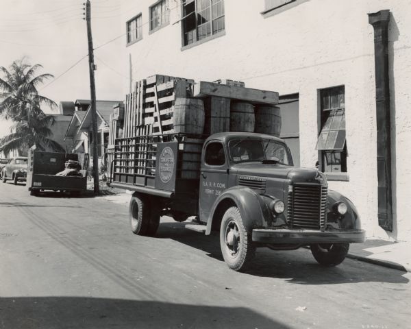 International K-6 truck loaded with wooden crates and barrels. Original caption: "This latest purchase, a K-6 International, made by the Union Transfer & Storage Company of Miami, Florida, is part of a fleet of seven units, four of which are Internationals. The truck shown is equipped with all-metal, 14-foot stake body with an Anthony hydraulically operated tail lift... Length of body including this tail lift is 17 feet."