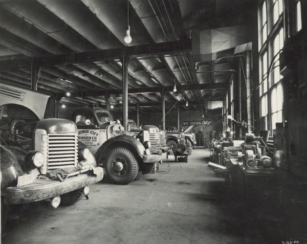 International Model K trucks in the shop. These trucks were owned and operated by Gateway City Transfer Company of La Crosse. A large sign on the back wall reads: "No Smoking!"