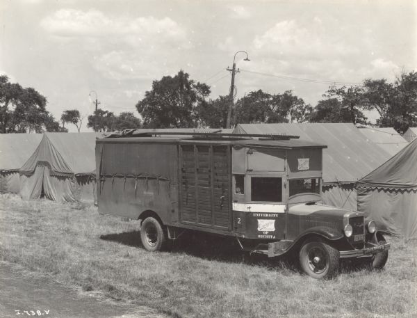 International truck parked in front of a group of tents. The bus is labeled: "University of Wichita" and "The Omnibus College."