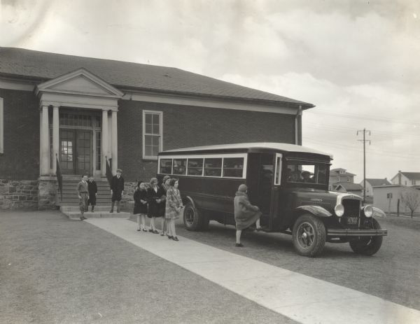 A group of warmly-dressed students are waiting in line to board the International A-4 York-Hoover School Bus. This bus was equipped with 185-inch wheelbase and body number 498-C.