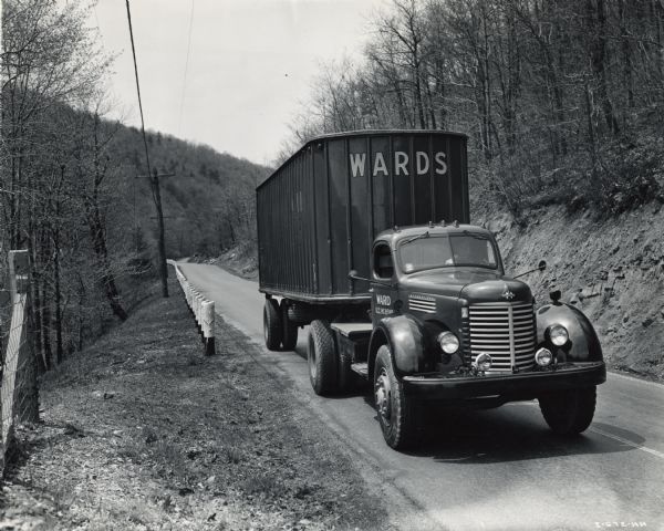 International KS-11 truck and semi-trailer shown traveling the highway leading out of Altoona. Original caption reads: "In traveling these mountainous roads the new KS-11 trucks pulling the full-load 28-foot trailers are proving most economical hauling units, averaging around 5 miles to the gallon."