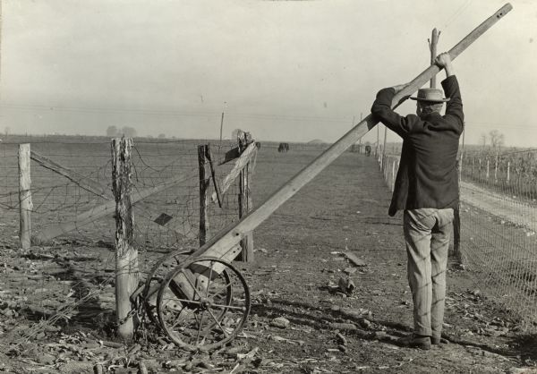 A man uses a "handy device for pulling old fence post" (original caption).