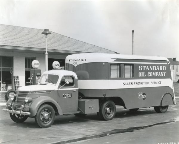 An International D-30 truck owned by the Standard Oil Company is parked in front of gasoline pumps at a service station.