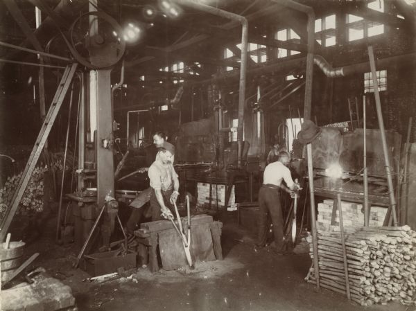 Men working with hot metal in what appears to be a forge at the McCormick Reaper Works factory.